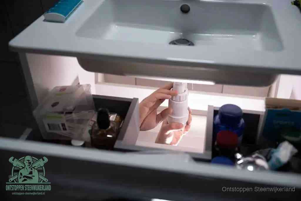 Een pompfles met zeep boven een wastafel, de heet water en afwasmiddel-methode om een vetprop in de afvoer los te maken in Steenwijkerland