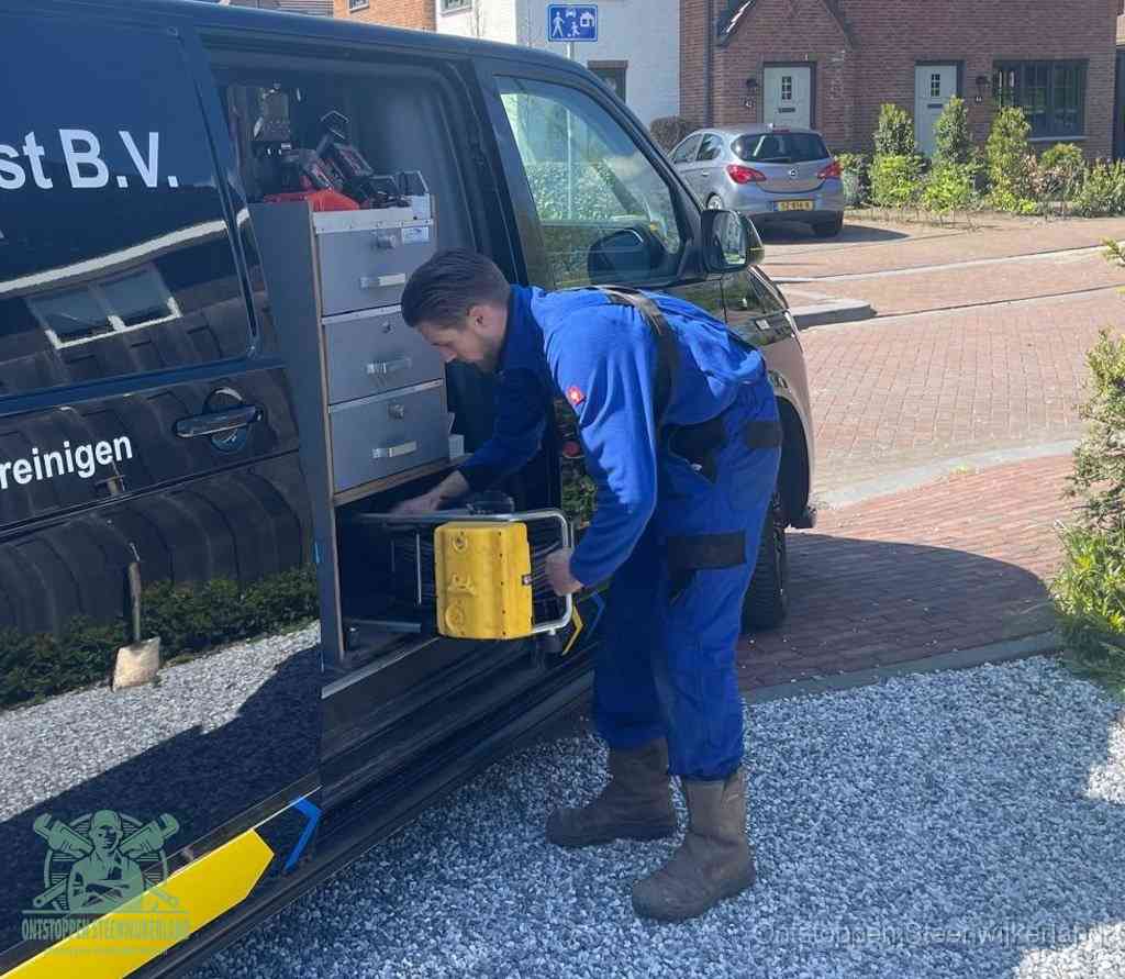 Een monteur pakt buiten op de oprit gereedschap uit de bedrijfsbus, het moment om een professional in te schakelen voor een verstopte afvoer in Steenwijkerland