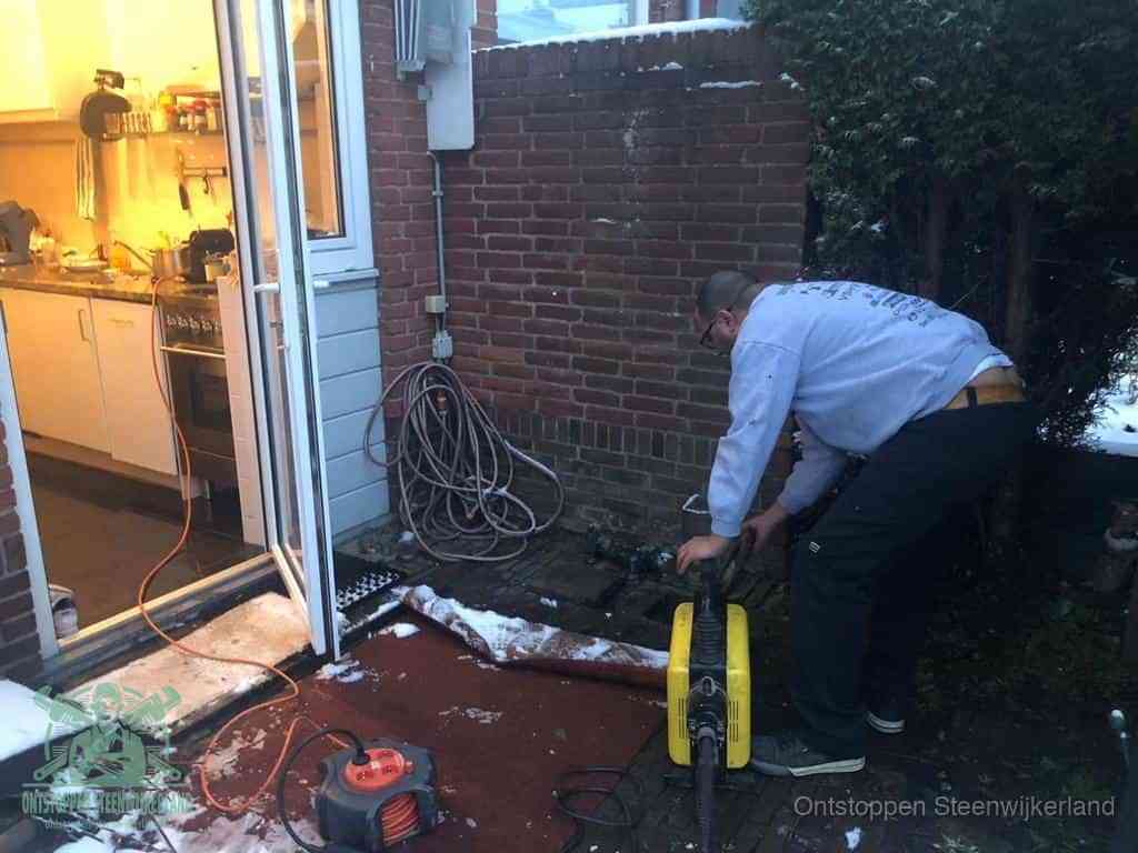 Een monteur werkt buiten bij een open riool-/grondput met een elektrische ontstoppingsmachine om een verborgen afvoerprobleem op te sporen in Steenwijkerland