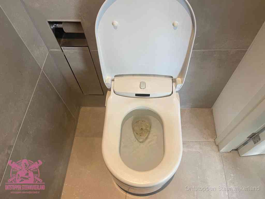 Een wit hangtoilet waarin een prop wc-papier op het water blijft drijven, een duidelijk signaal van een verstopte wc in Steenwijkerland