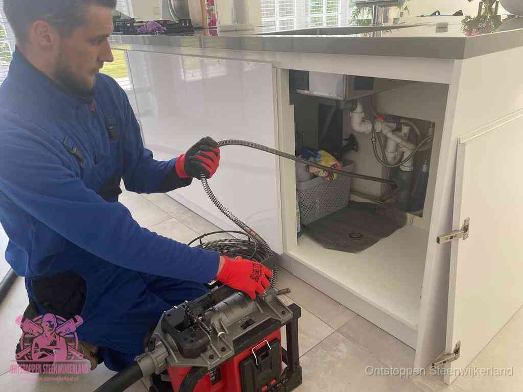 Een monteur reinigt de keukenafvoer grondig met een veermachine om terugkerende gootsteenverstoppingen te voorkomen in Steenwijkerland