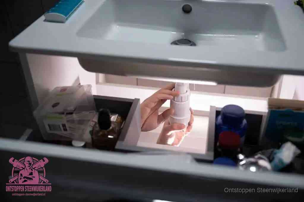 Een pompfles met zeep boven een wastafel in de toiletruimte, de warm water en afwasmiddel-methode om de wc te ontstoppen in Steenwijkerland