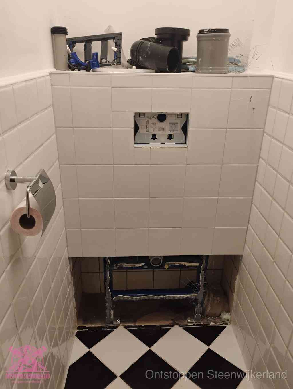 Een toiletruimte waar het hangtoilet en de inbouwreservoir-onderdelen zijn vrijgelegd voor onderhoud, periodiek nazicht voorkomt een wc-verstopping in Steenwijkerland
